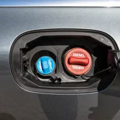Dwa korki wlewu paliwa samochodu: niebieski z napisem AdBlue i czerwony z napisem Diesel.
