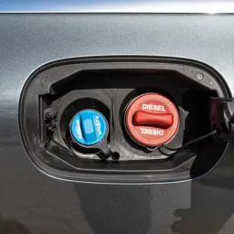 Dwa korki wlewu paliwa samochodu: niebieski z napisem AdBlue i czerwony z napisem Diesel.
