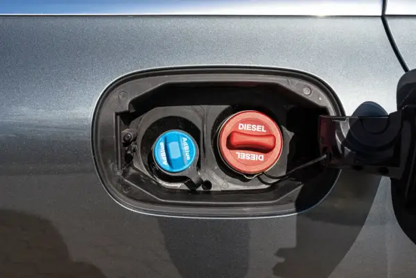 Dwa korki wlewu paliwa samochodu: niebieski z napisem AdBlue i czerwony z napisem Diesel.